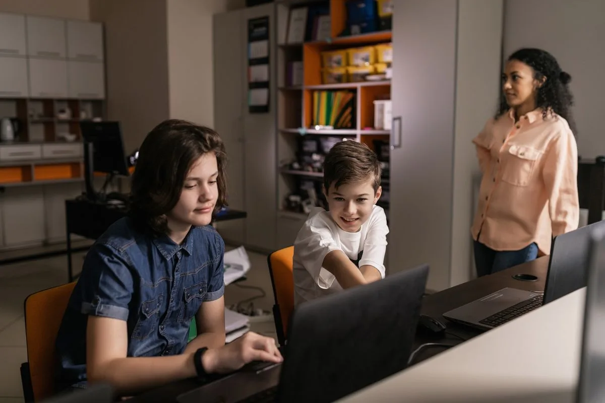 A staff member and students reviewing something on a laptop
